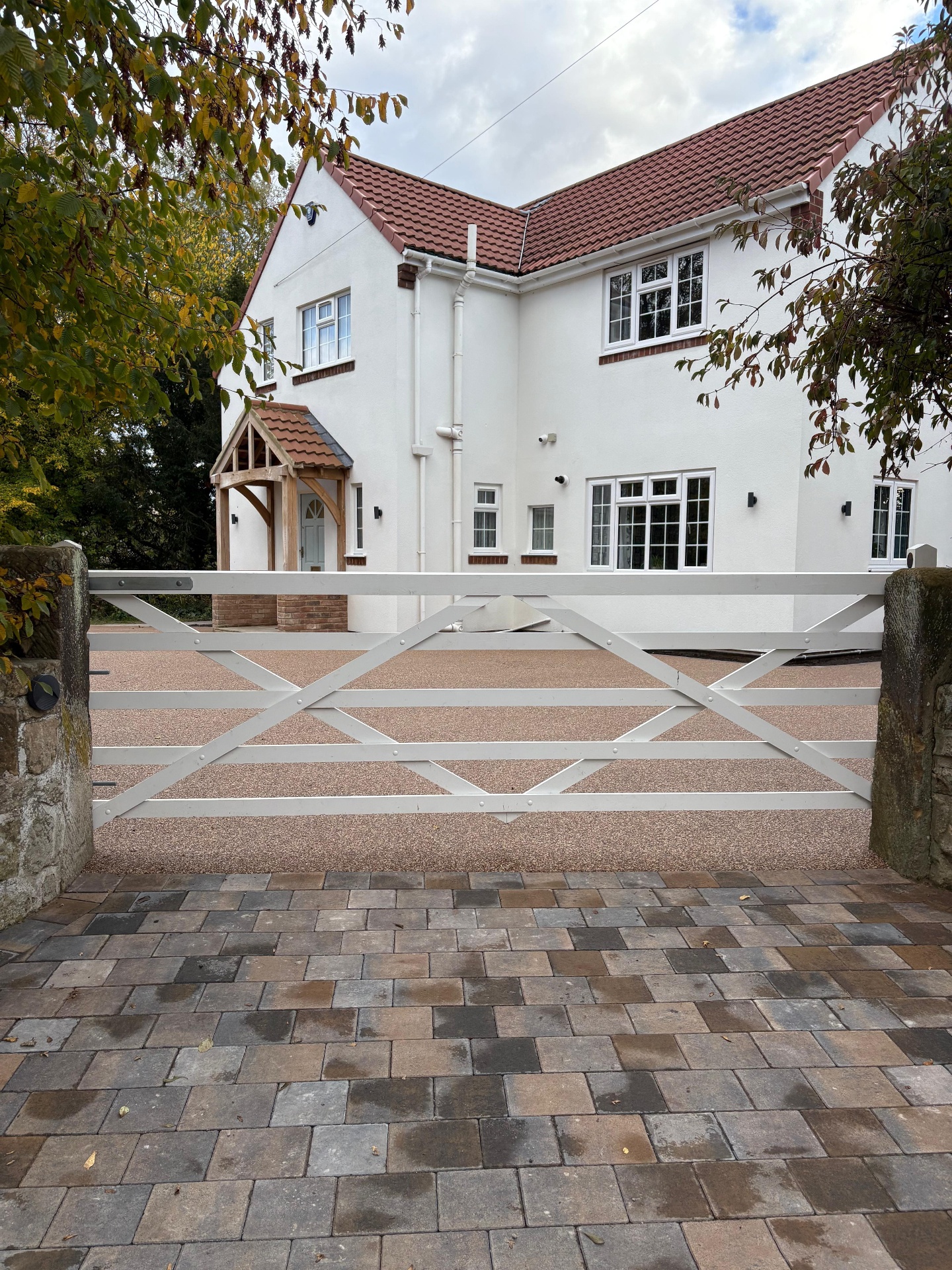 Block paved driveway and entrance with white gate at a completed property