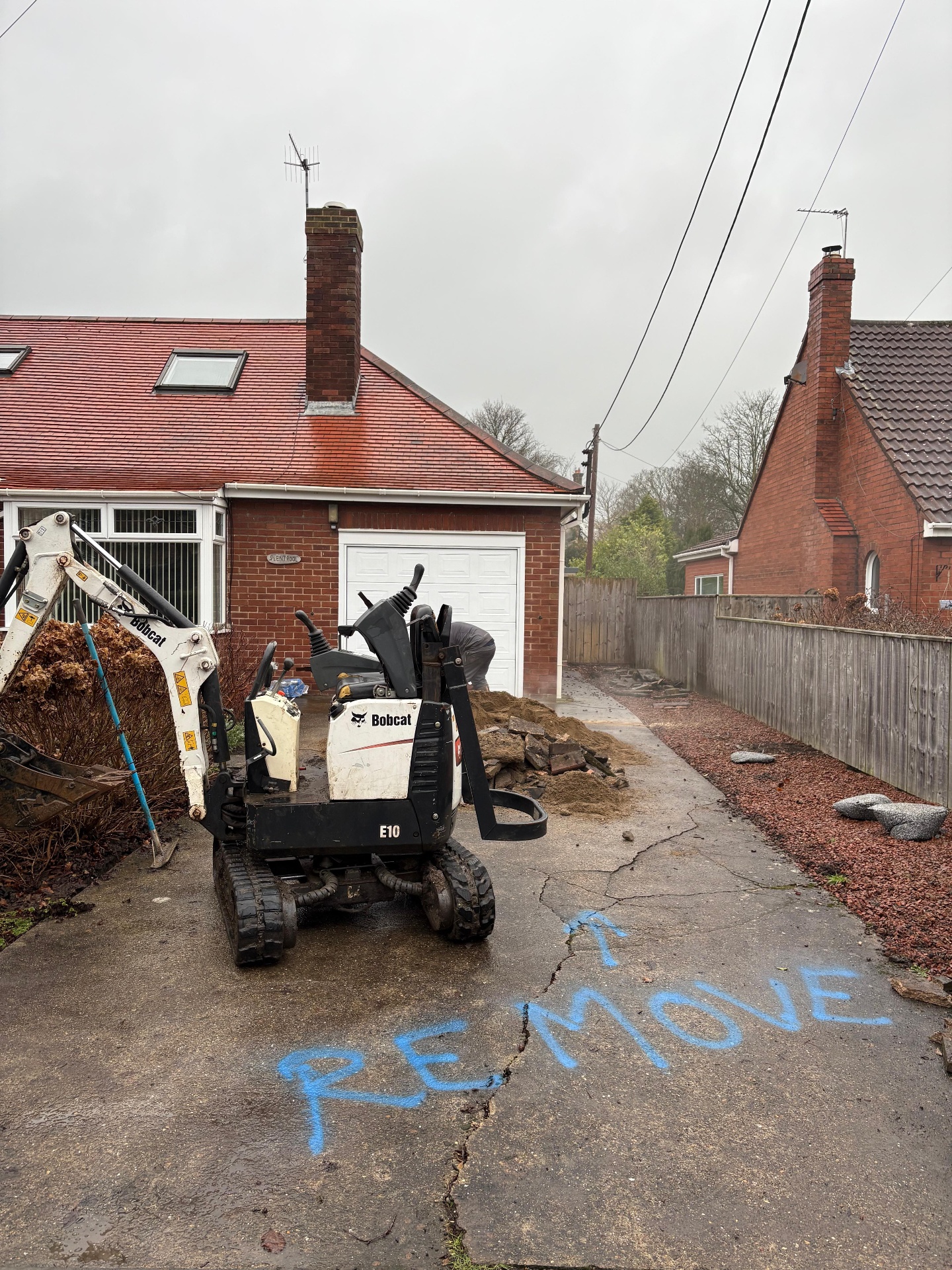 Mini digger removing a failed driveway surface during repair and replacement work