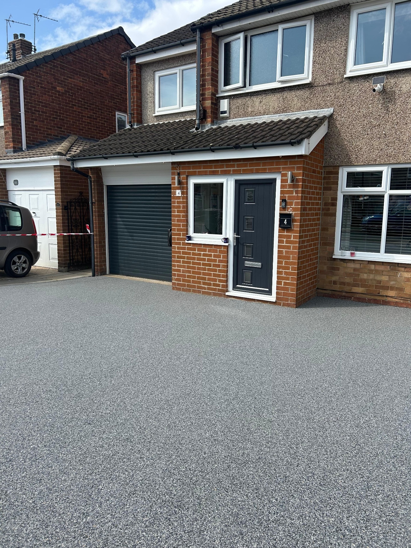 Pale resin driveway installed beside a garage and front entrance